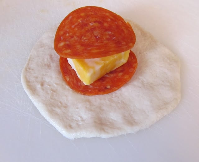 slices of pepperoni and cube of cheese on dough