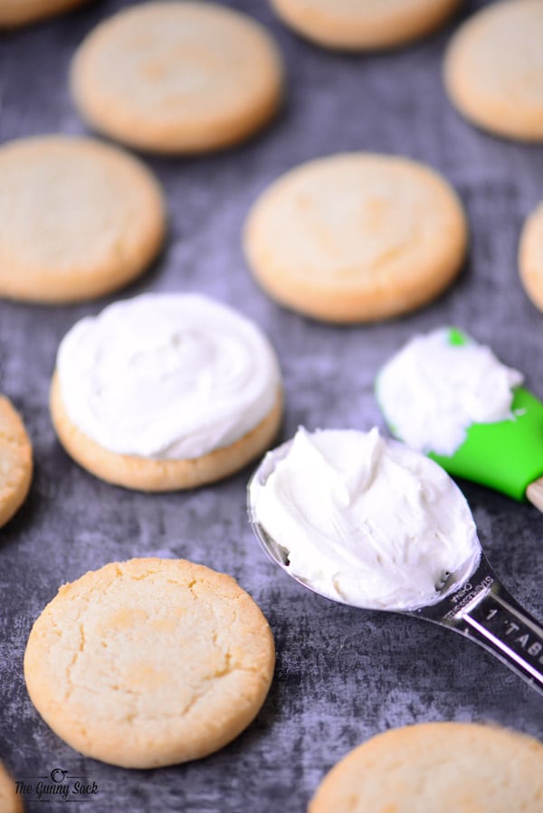 Cookies being covered in cream cheese frosting