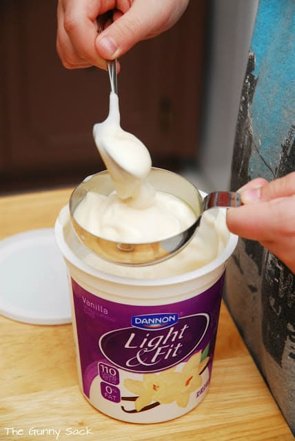 spooning yogurt into a measuring cup
