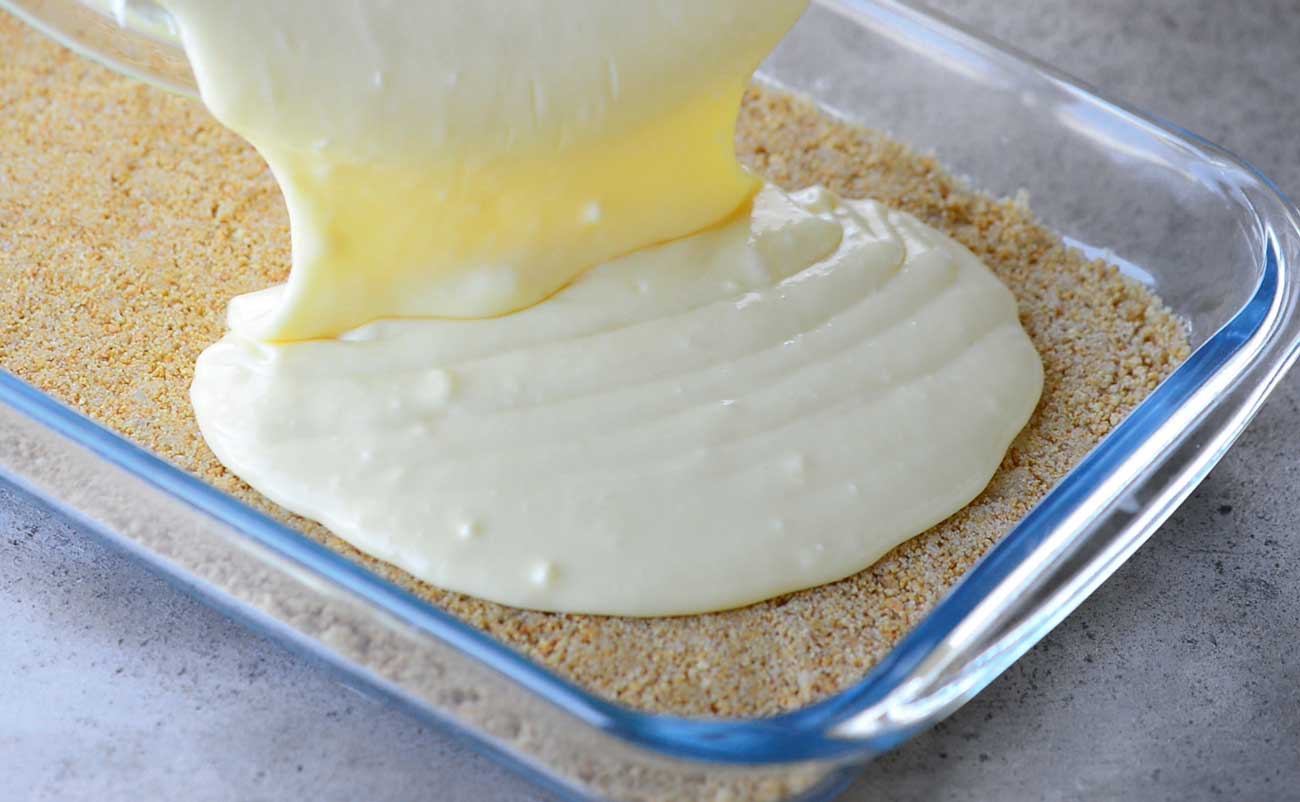 pouring cheesecake batter into pan