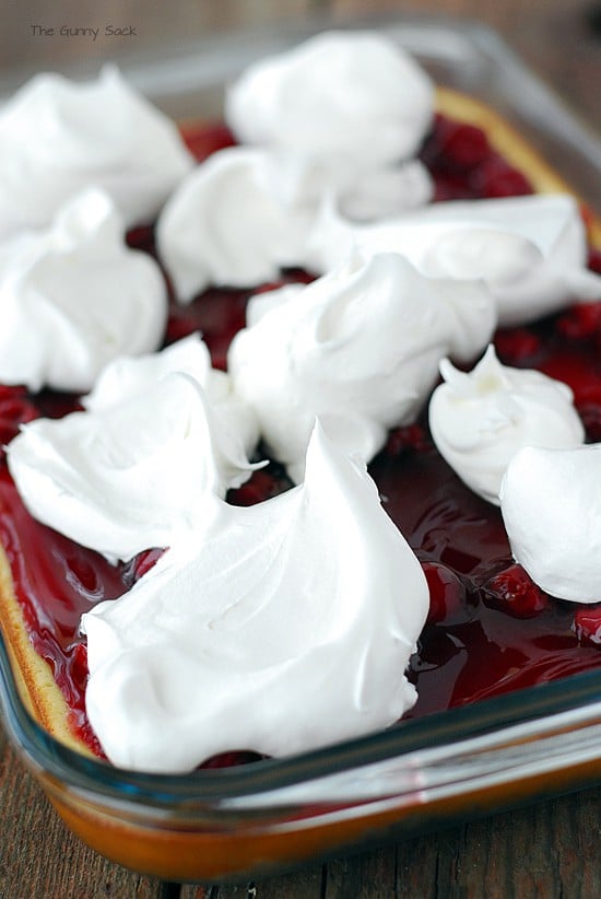 cool whip on top of cherry pie filling on cheesecake in a nine by thirteen inch pan