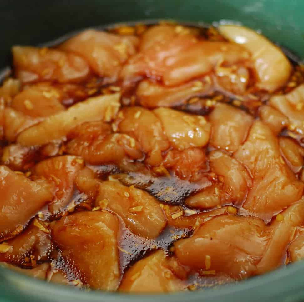 raw chicken with sauce in slow cooker