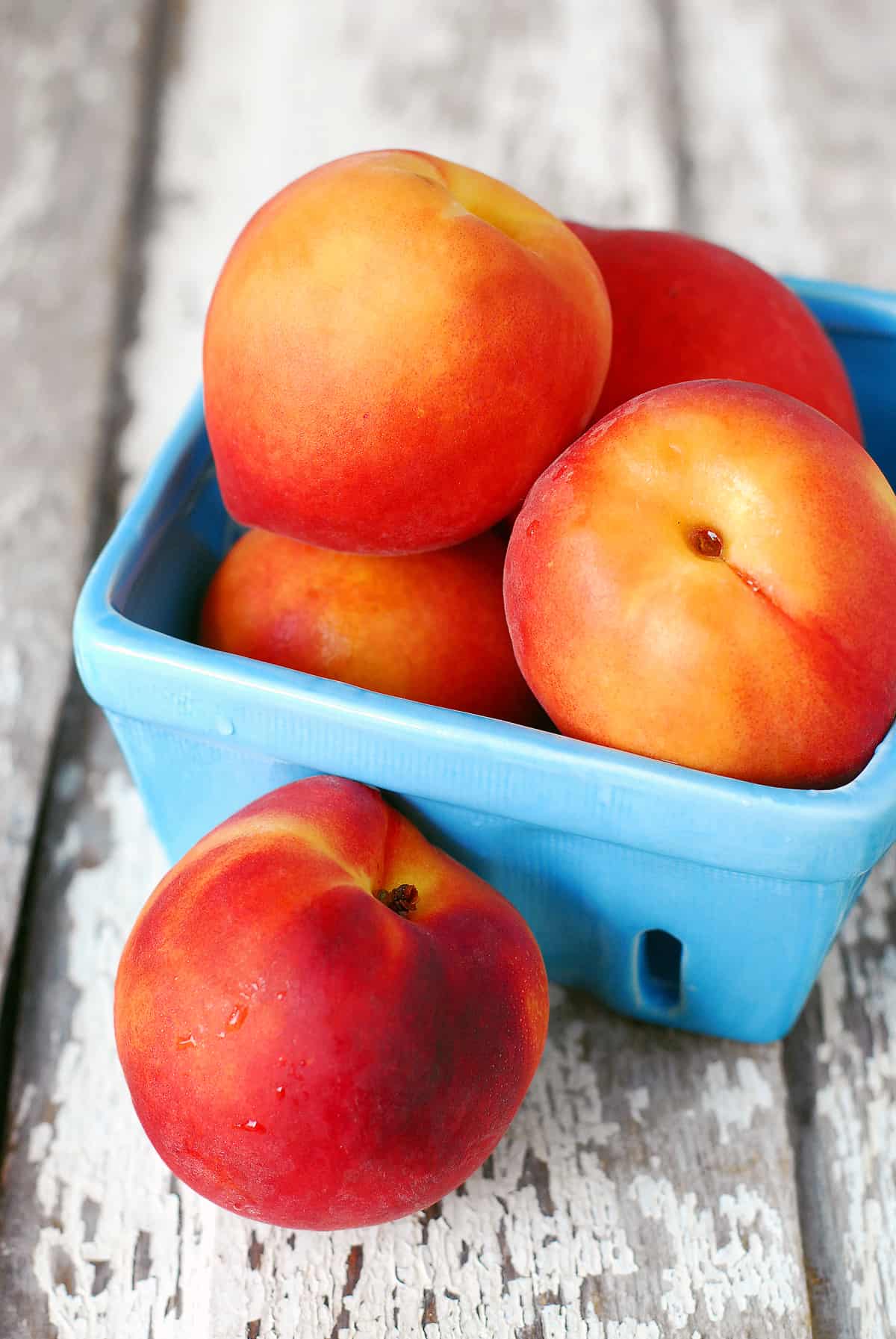 Fresh peaches in a blue container.