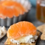 cracker with cream cheese and a tangerine on top