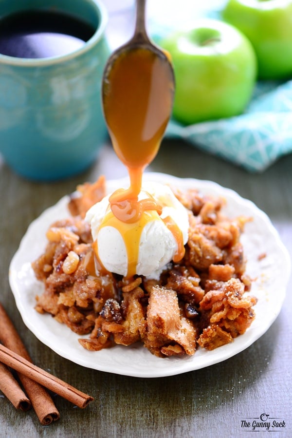 caramel being drizzled from a spoon onto apple walnut bread pudding