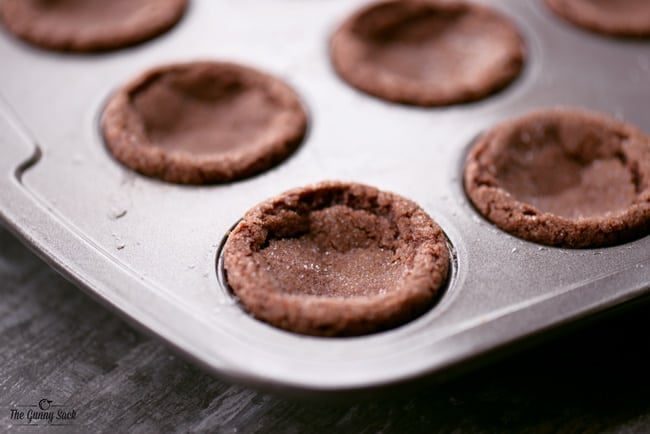 baked peppermint hot chocolate cookie cups in a mini muffin pan