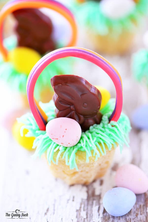 Easter basket cookie cups with buttercream frosting grass, a chocolate Easter bunny, chocolate eggs and a licorice handle