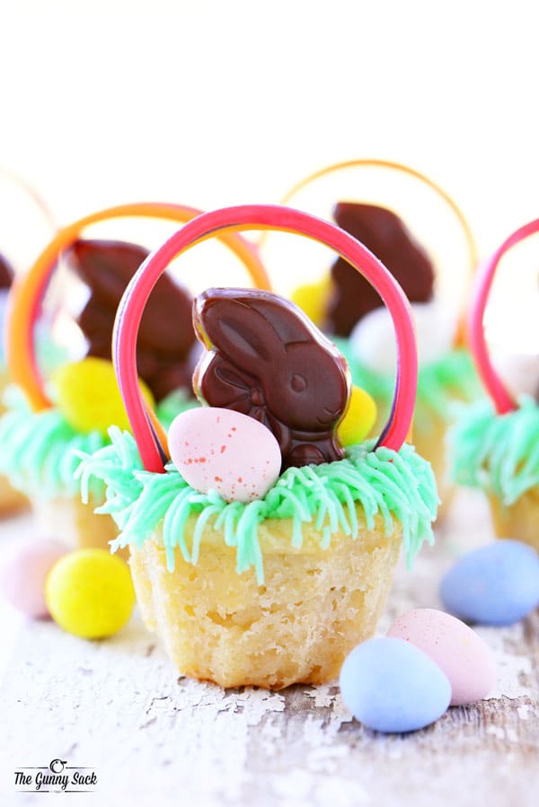 Easter basket cookie cups with grass frosting, a chocolate bunny, and chocolate eggs