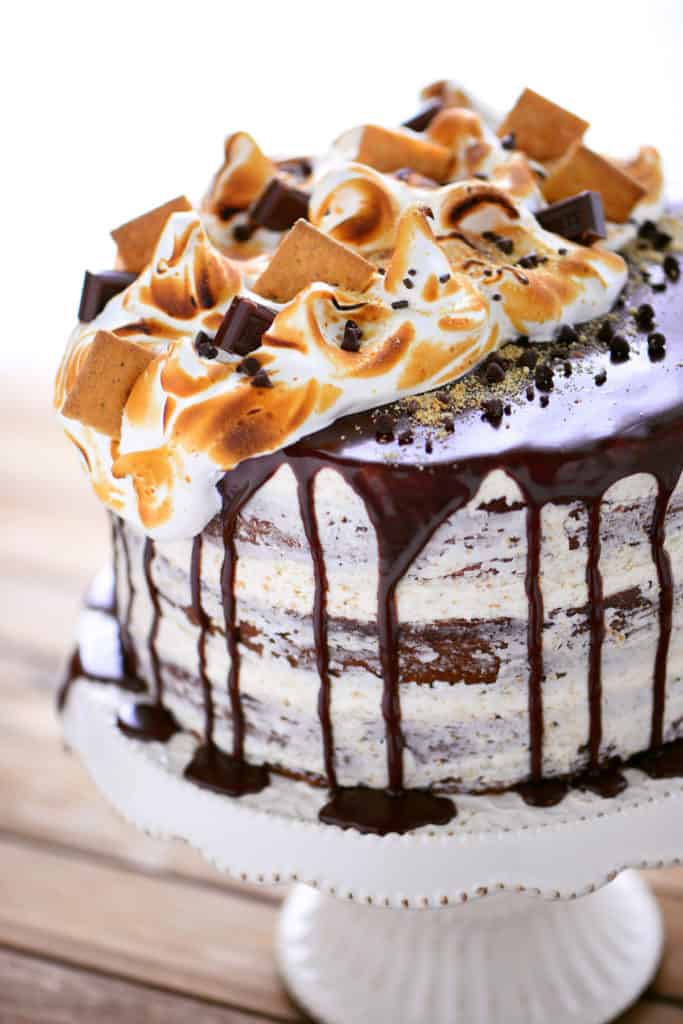 smores cake with chocolate ganache and toasted meringue topping on a cake stand