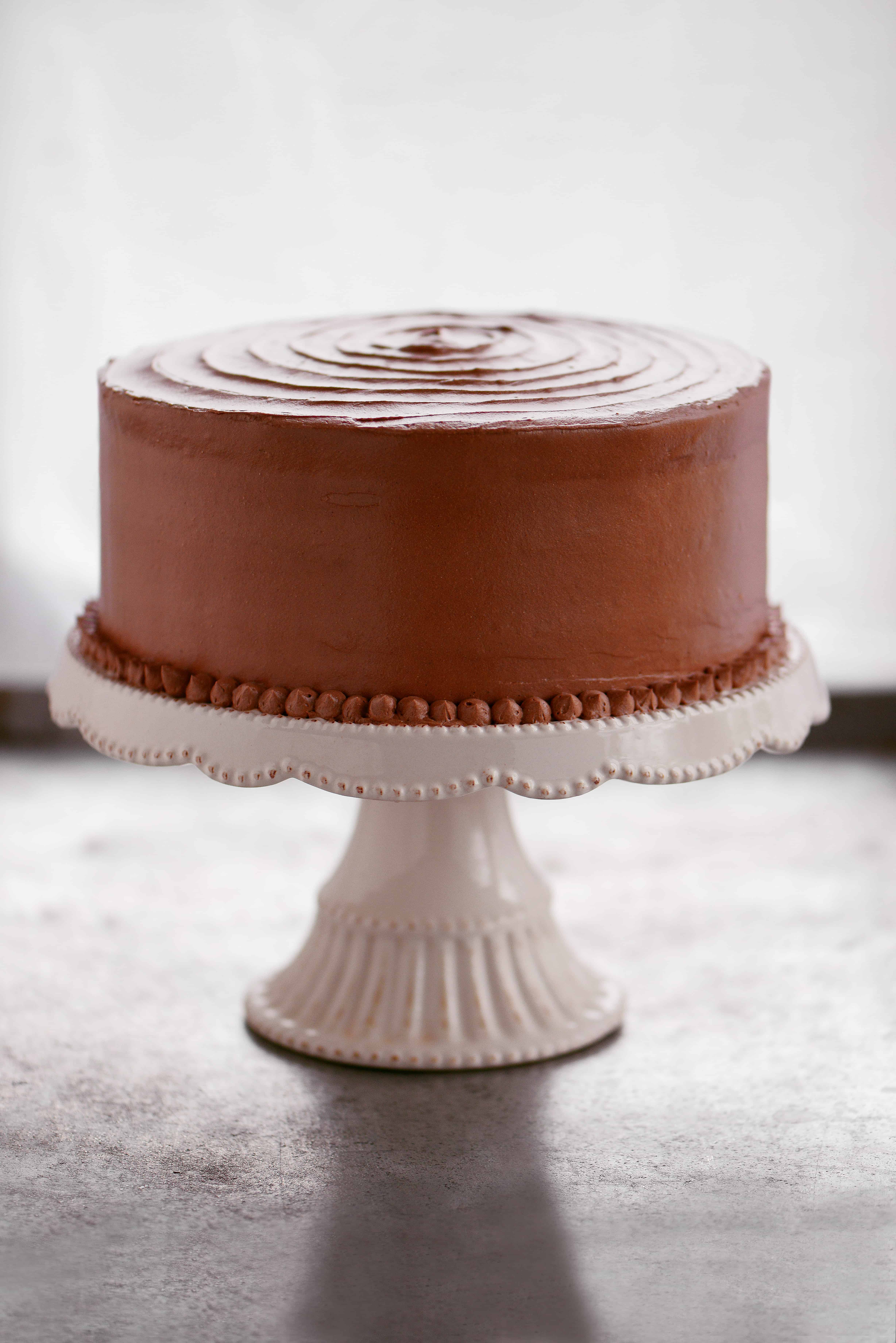 chocolate layer cake on a white cake stand