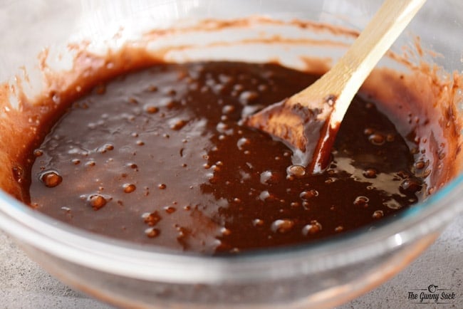 brownie batter in a glass bowl with a wooden spoon