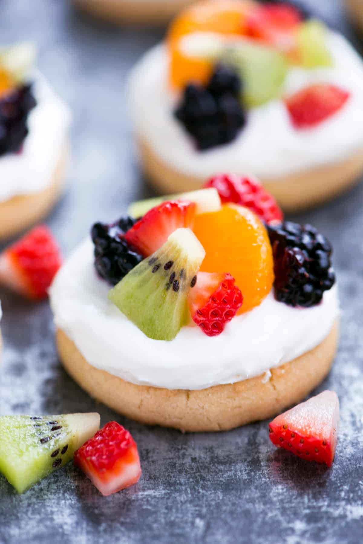 Mini fruit pizzas with cream cheese frosting and diced fruit.