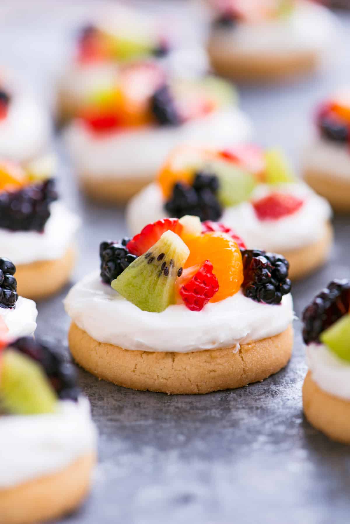 Mini fruit pizza with frosting and diced fruit.