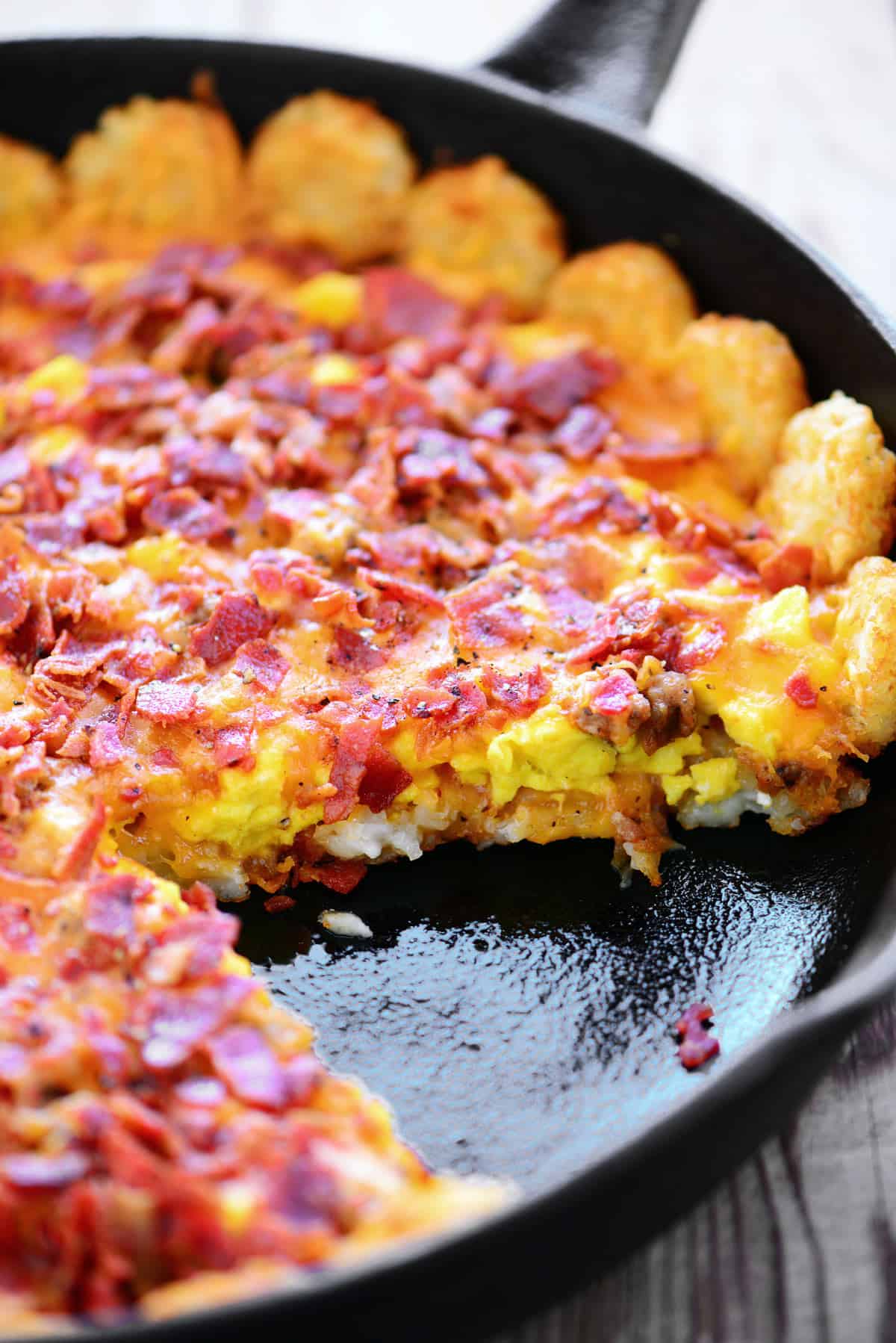 Tater tot breakfast pizza with a slice removed.