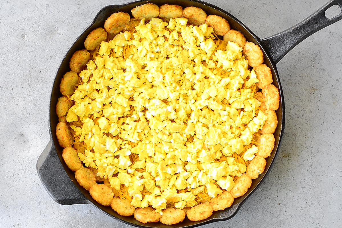 Scrambled Eggs On Top Of Cheese And Tater Tots In A Pan