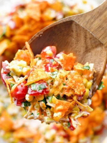 A wooden spoonful of corn salad with Doritos.