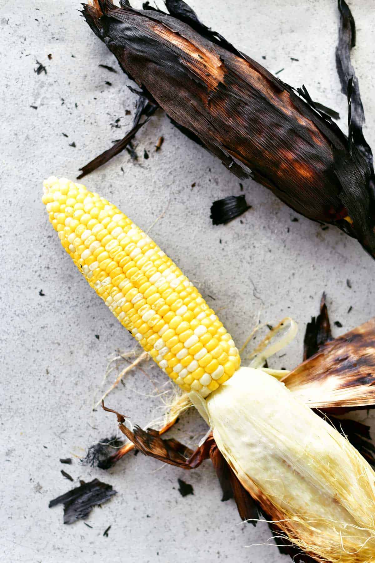 peeling grilled corn on the cob with the husks