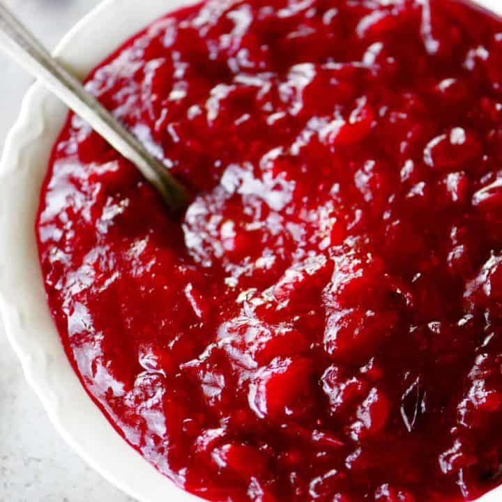 homemade cranberry sauce in a white bowl with a spoon