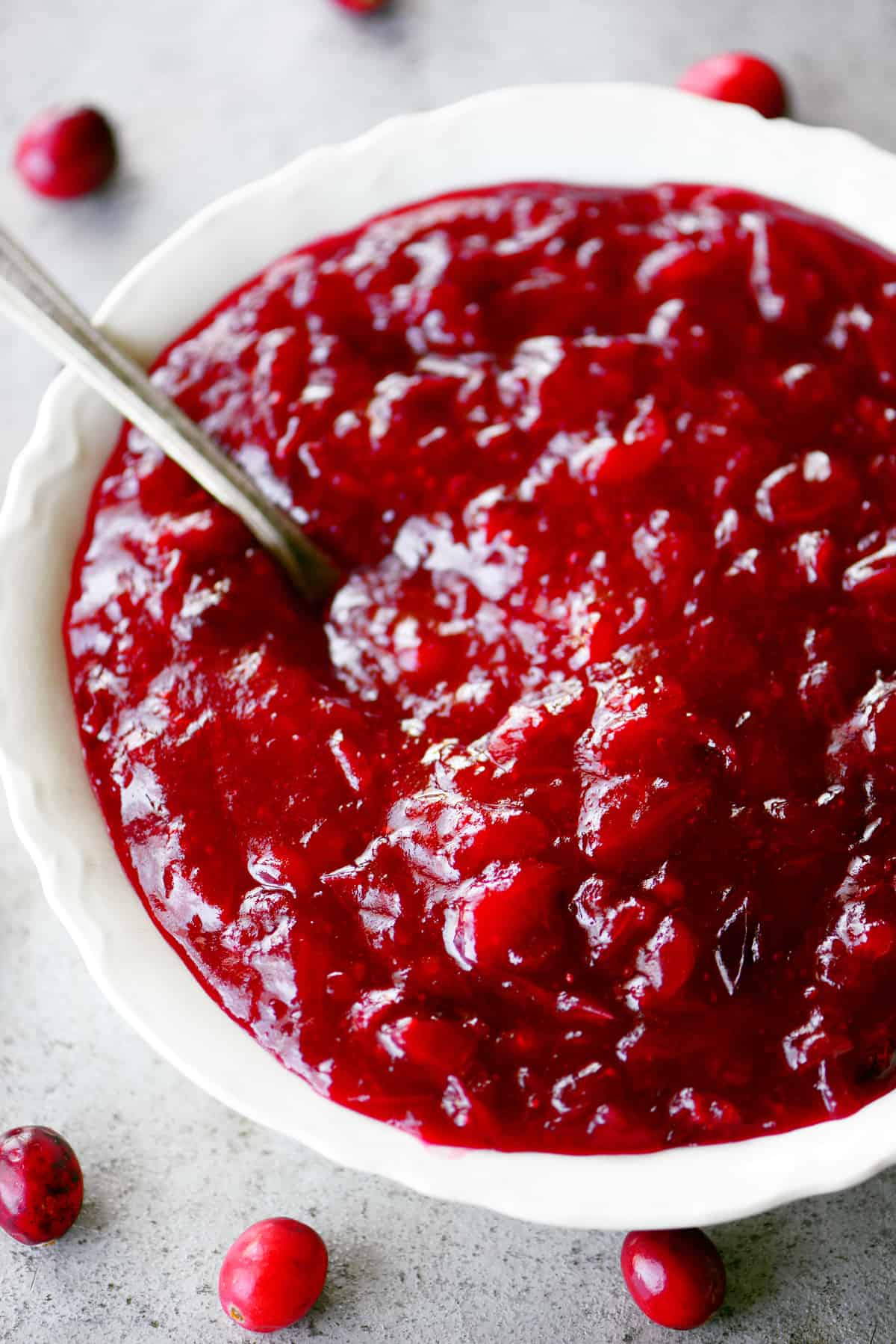homemade cranberry sauce in a white bowl with a spoon