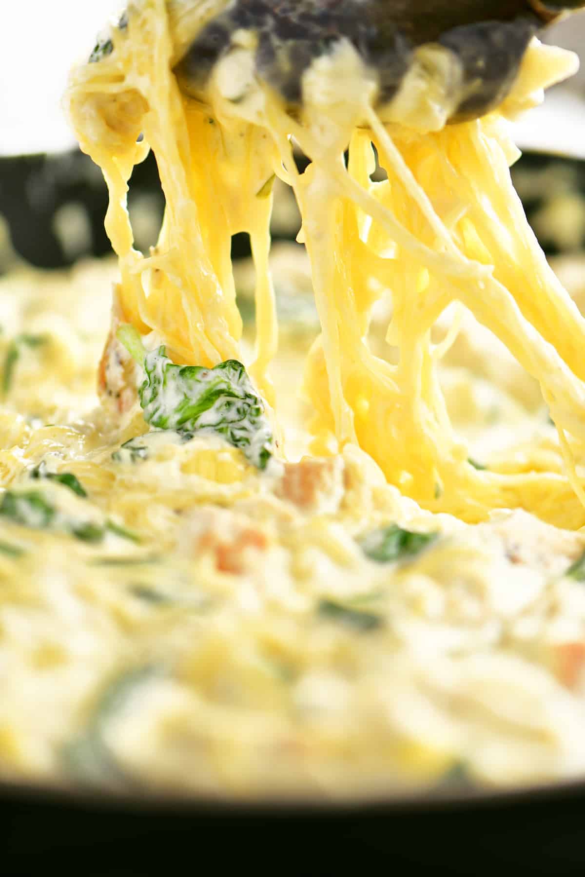 scooping spinach artichoke spaghetti squash with chicken from skillet