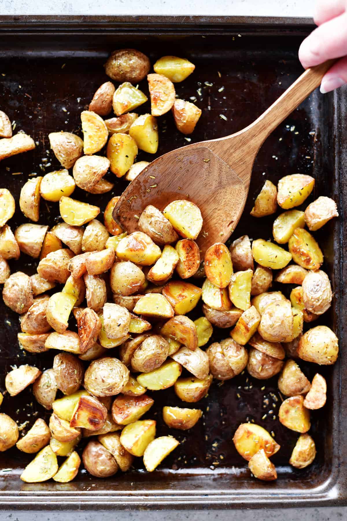 oven roasted potatoes in sheet pan with wooden spoon