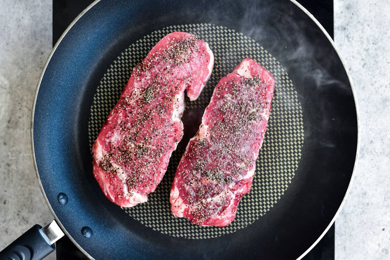 two seasoned steaks in a skillet