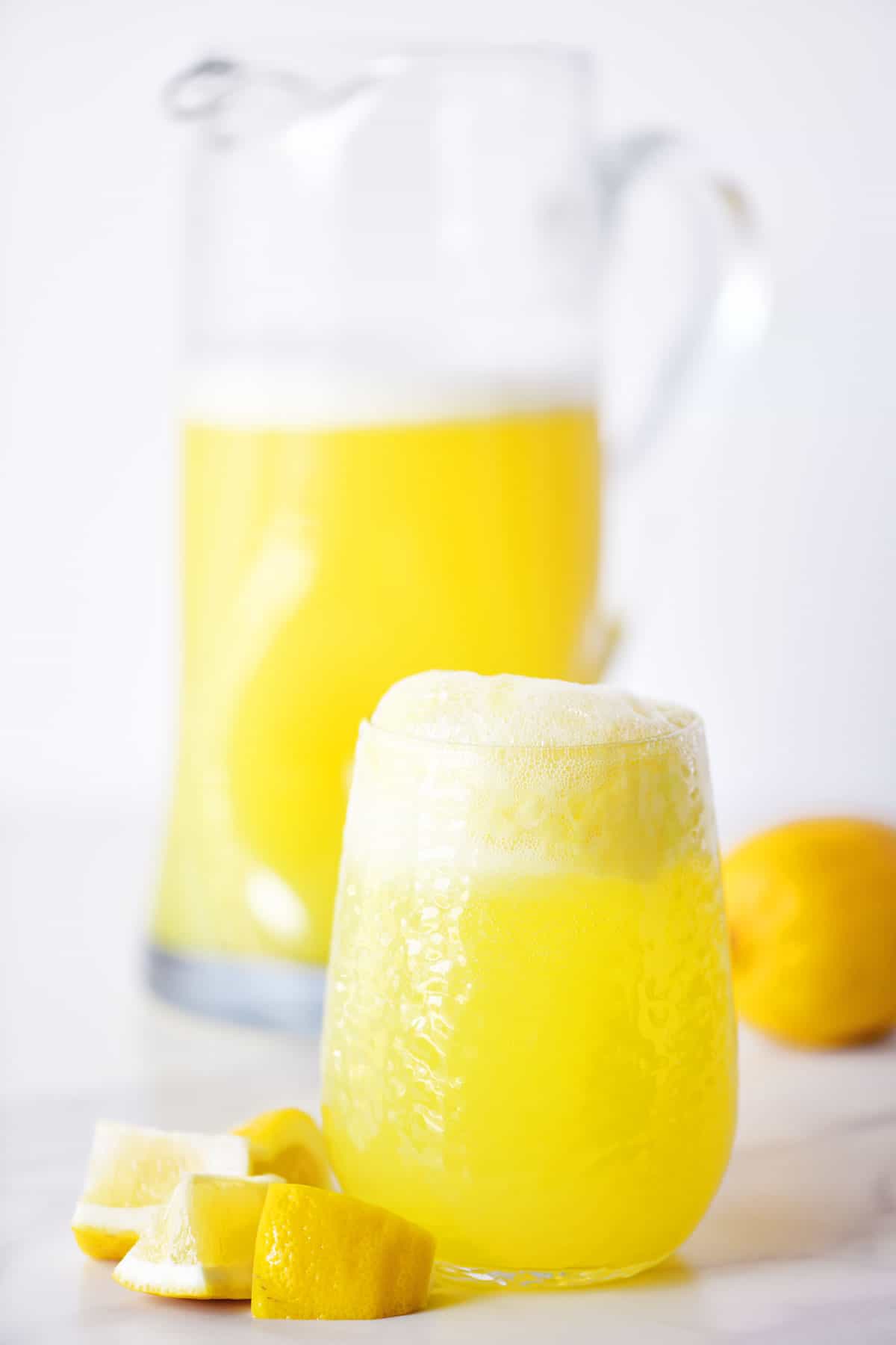 lemon sherbet punch in a glass and pitcher with lemon wedges