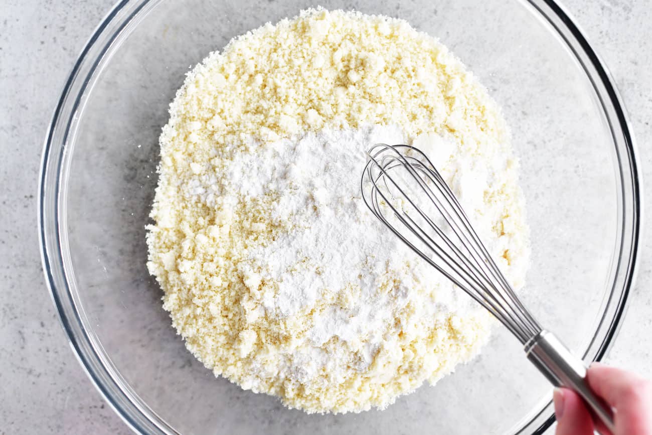 almond flour and baking powder in a glass bowl with a metal whisk
