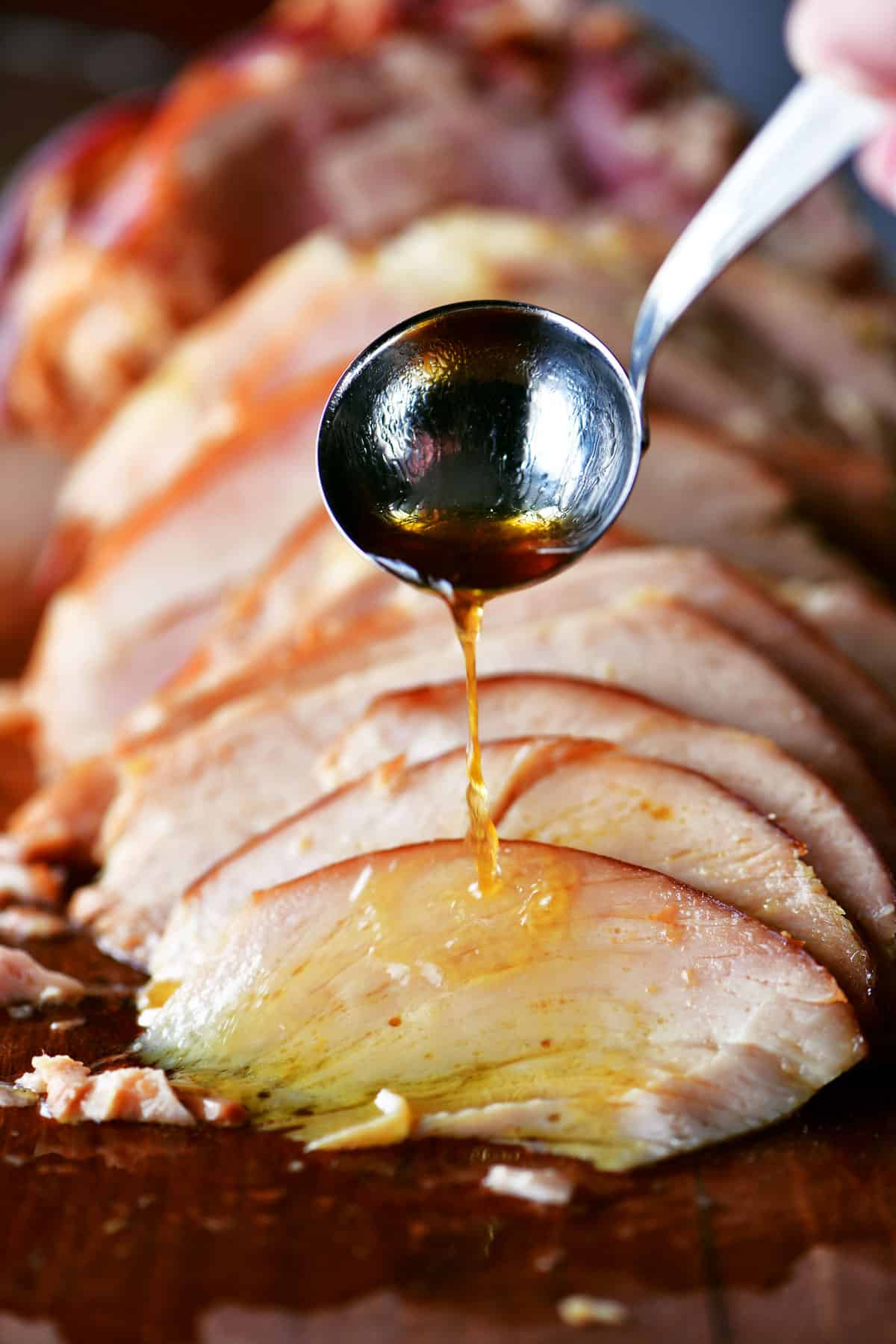 ham drippings being ladled over sliced ham