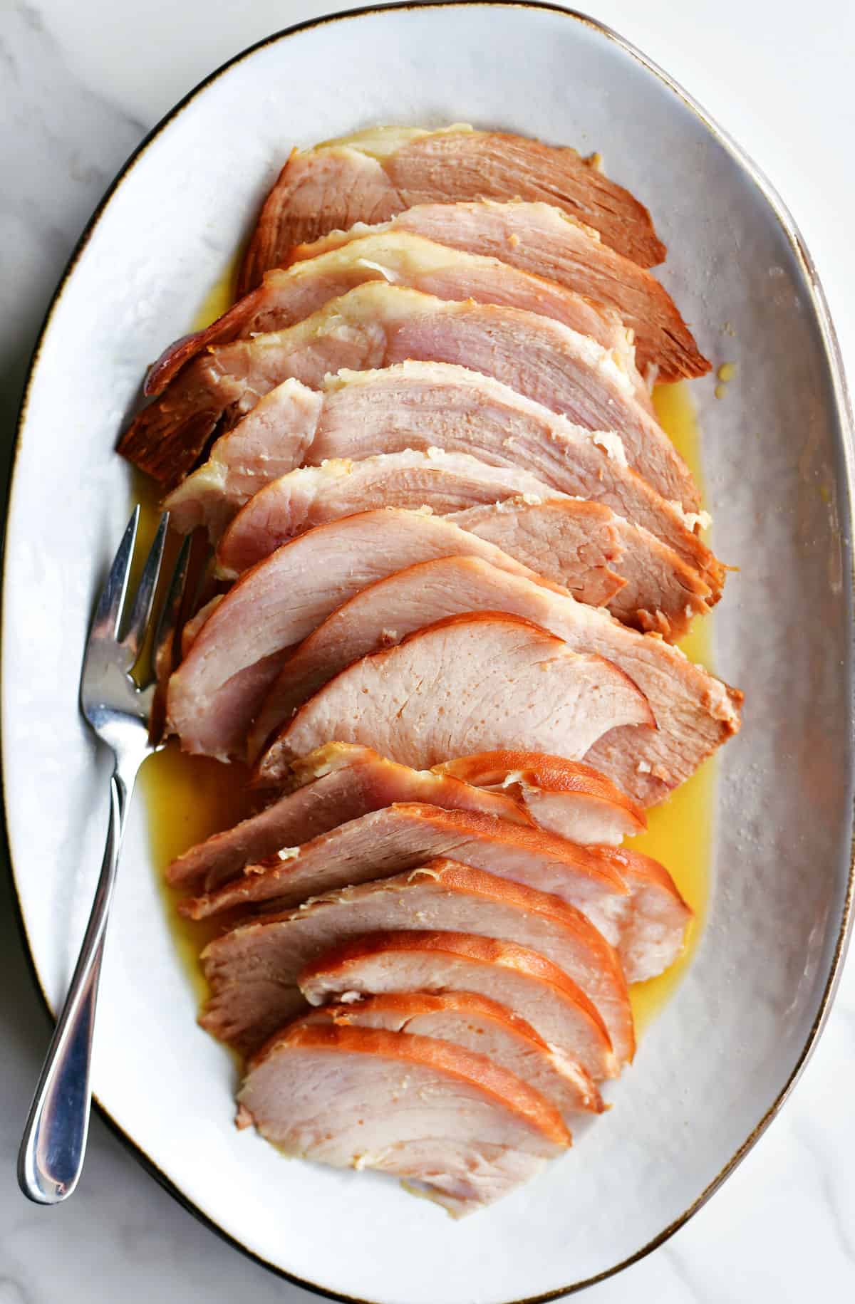sliced slow cooker ham on a white platter