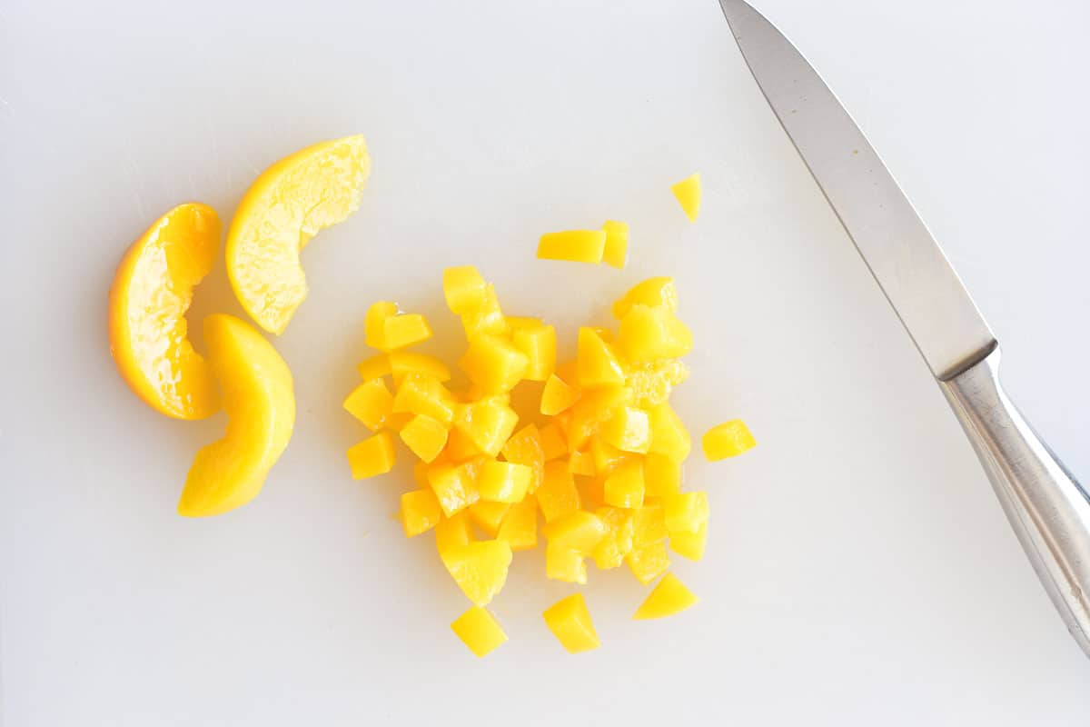 diced peaches on a cutting board with a knife