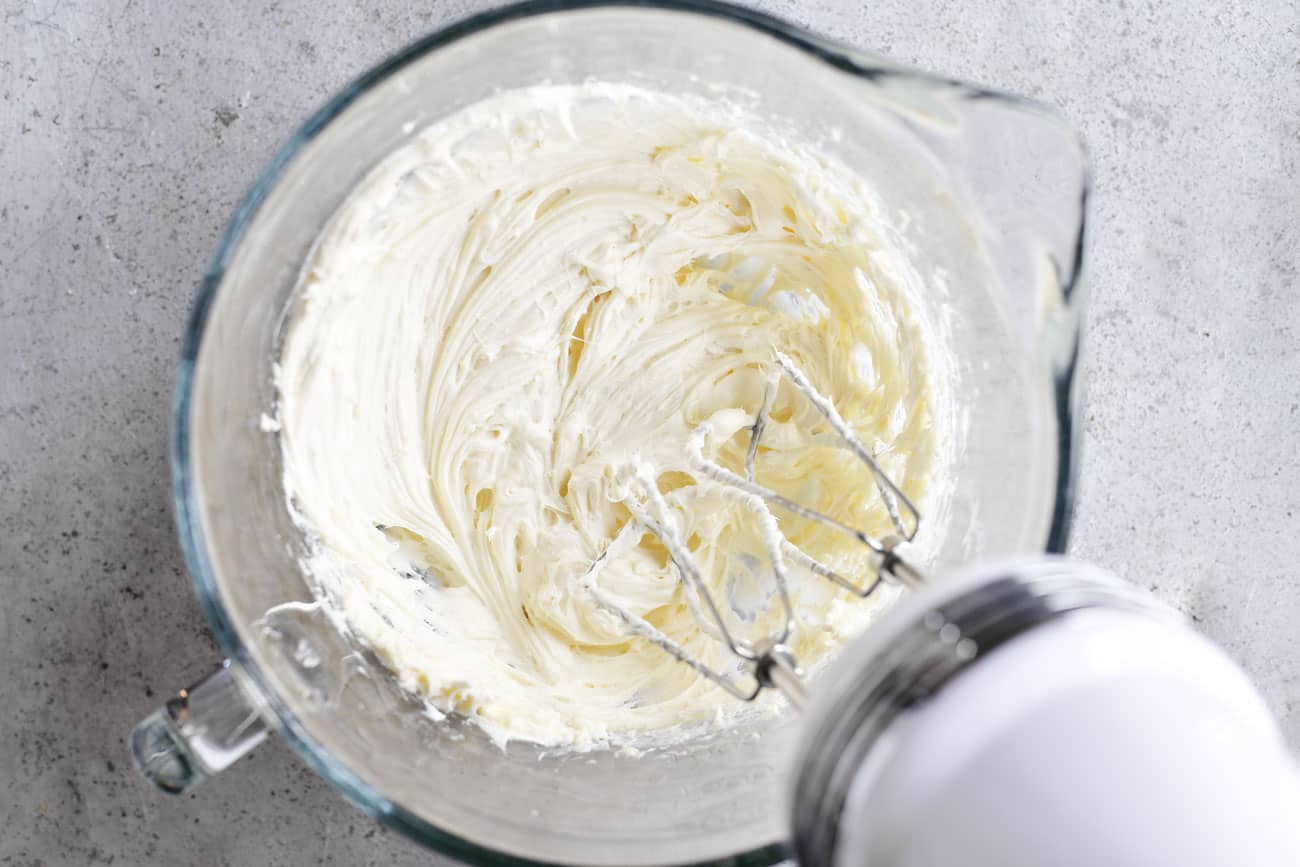 beating cream cheese and sugar in a glass bowl