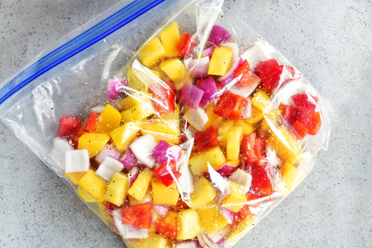 sliced onions, red peppers, pineapple, and mango in a plastic baggie