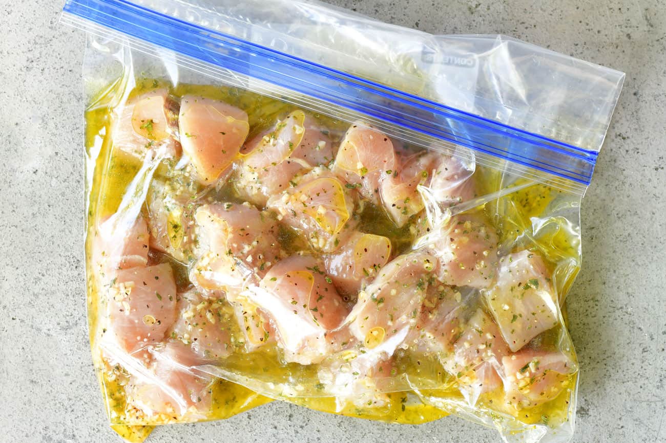cubed chicken in marinating in a gallon sized ziptop bag