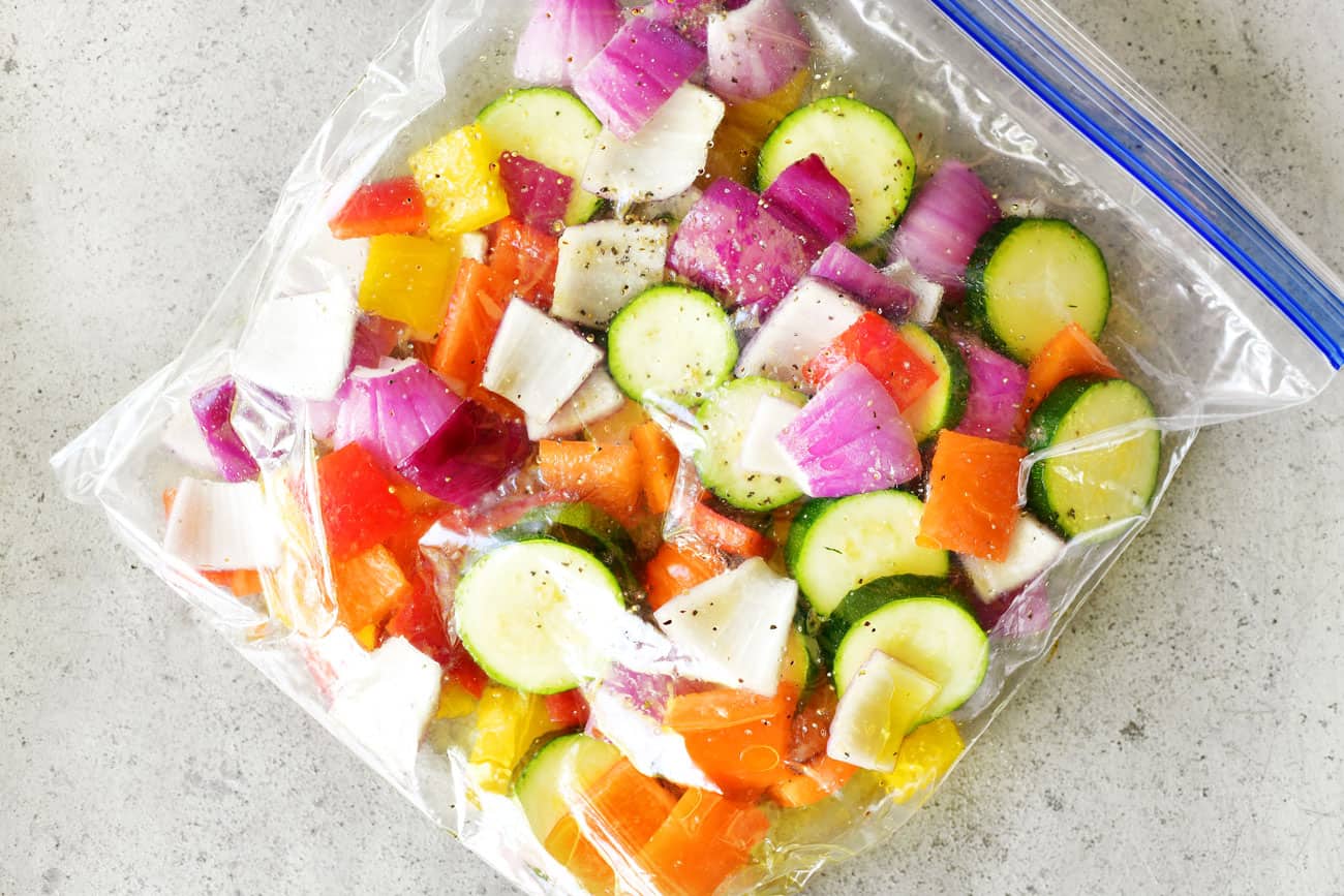 sliced onions, peppers, and zucchini in a gallon sized ziptop bag