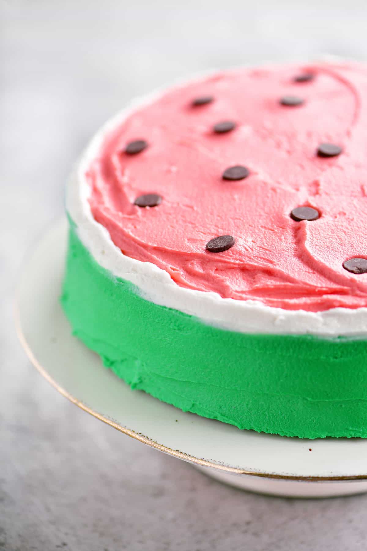 frosted watermelon cake on a white cake stand