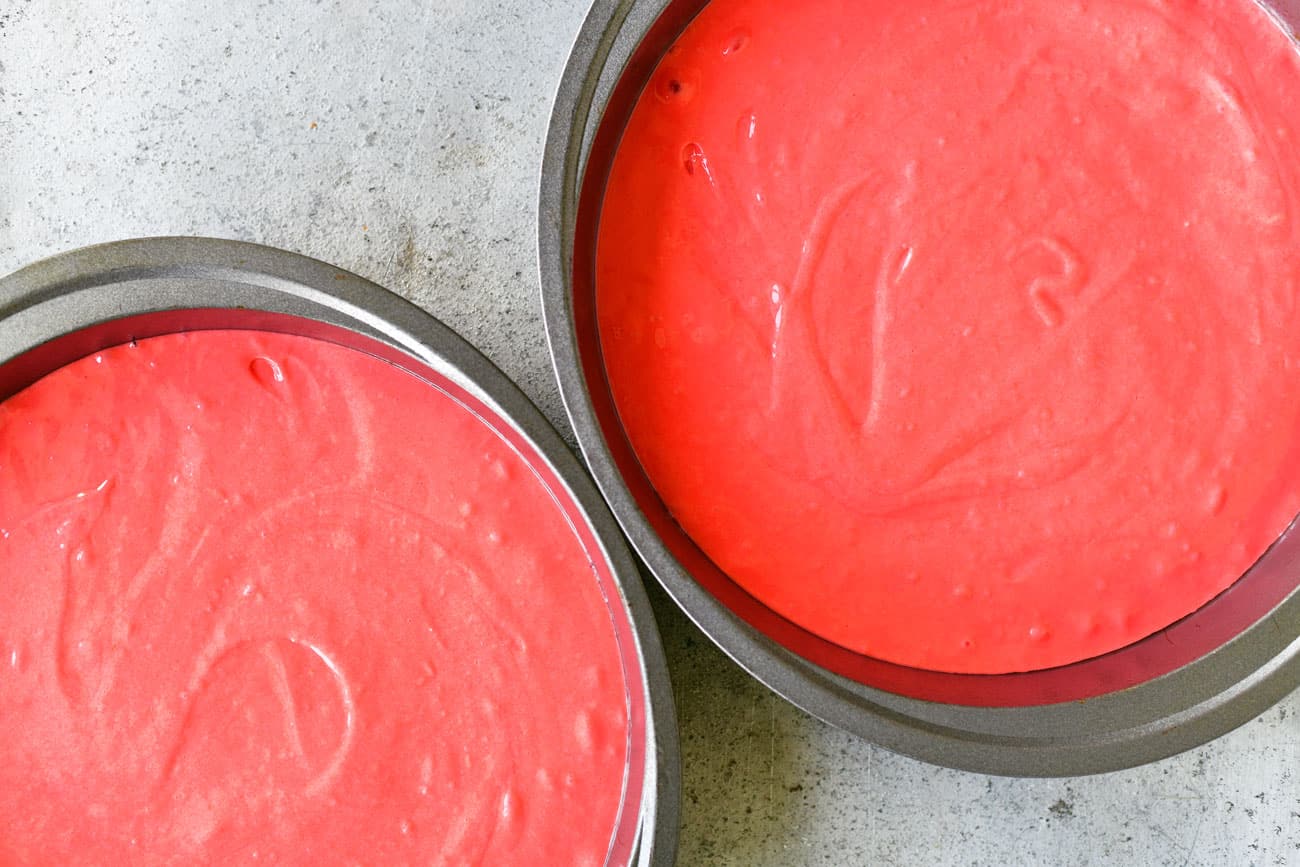 pink cake batter in two pans