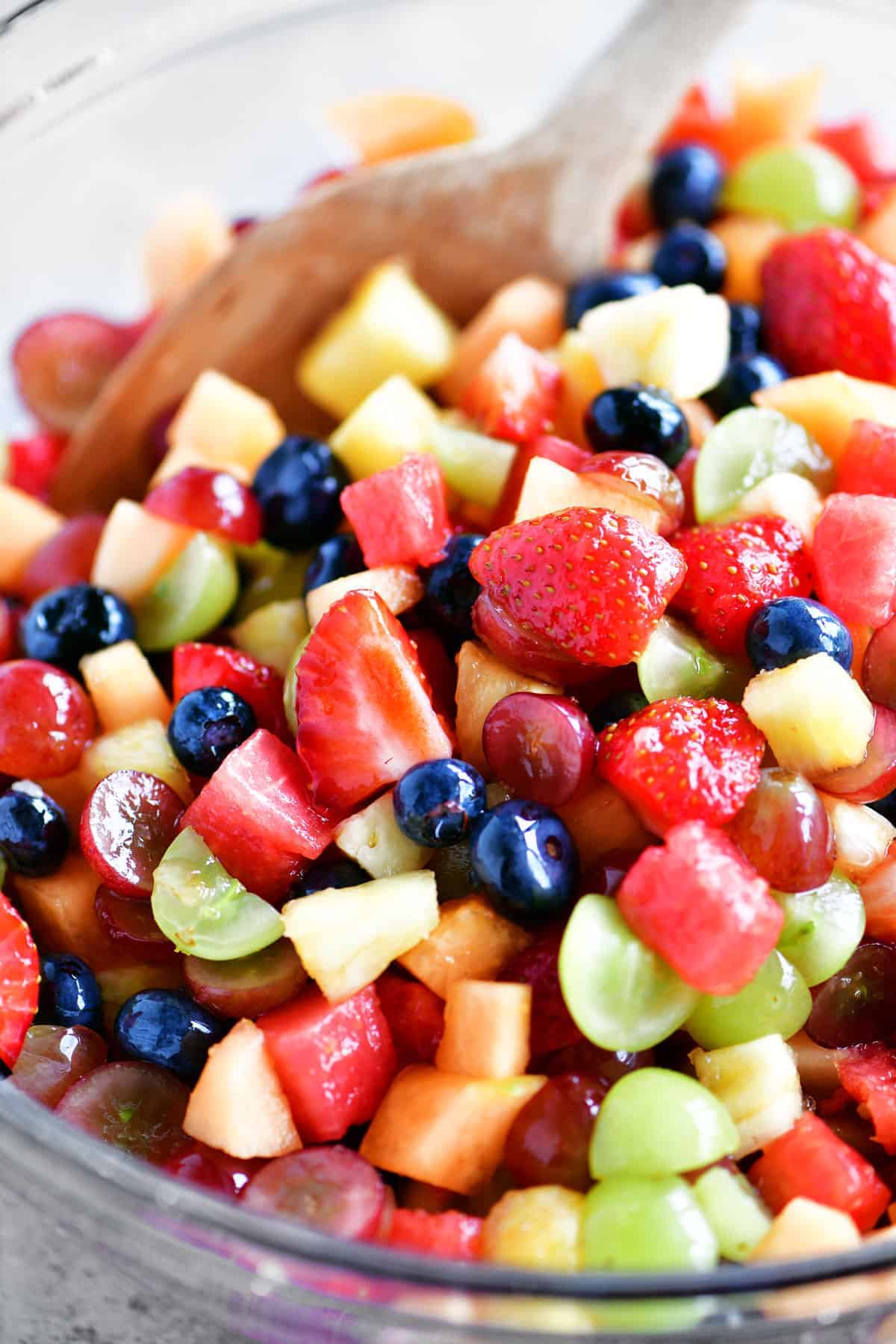fruit salad in a bowl with a wooden spoon