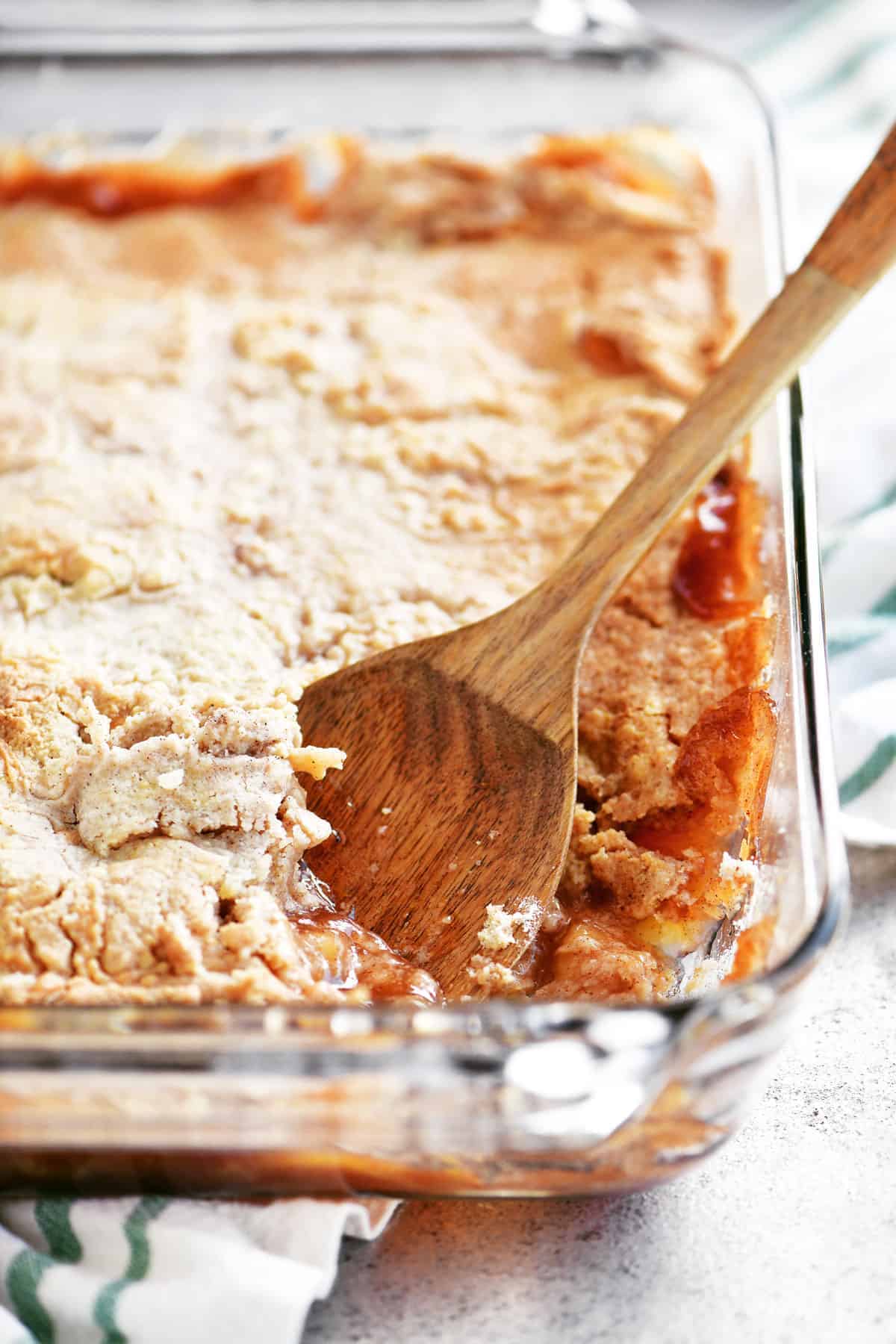 apple cobbler in a pan with a wooden spoon