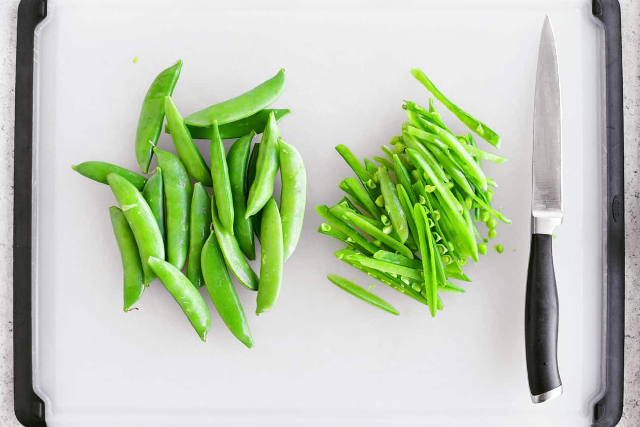 sliced snap peas on a cutting board