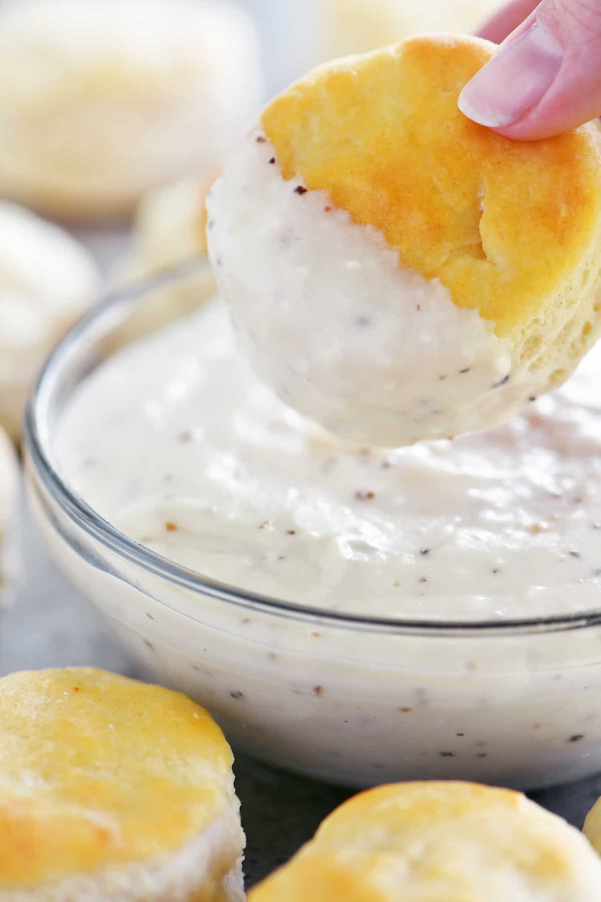 mini biscuit dipped in bowl of white gravy
