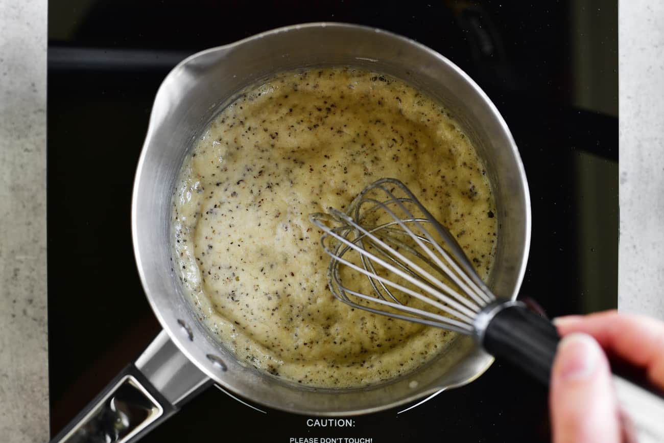 whisking flour into gravy in saucepan