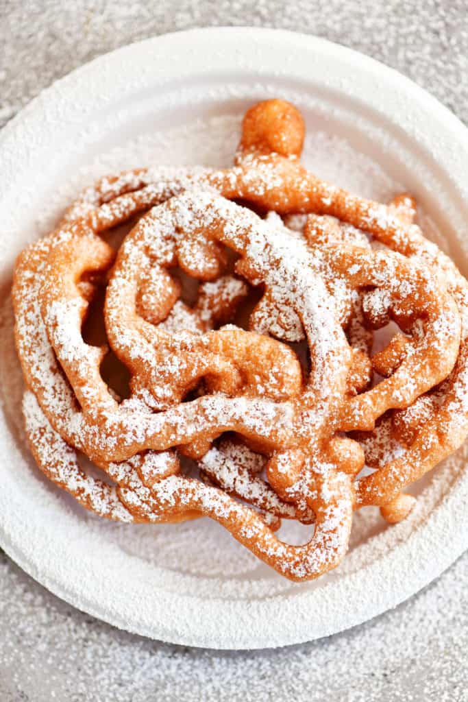 funnel cake with powdered sugar on a white plate