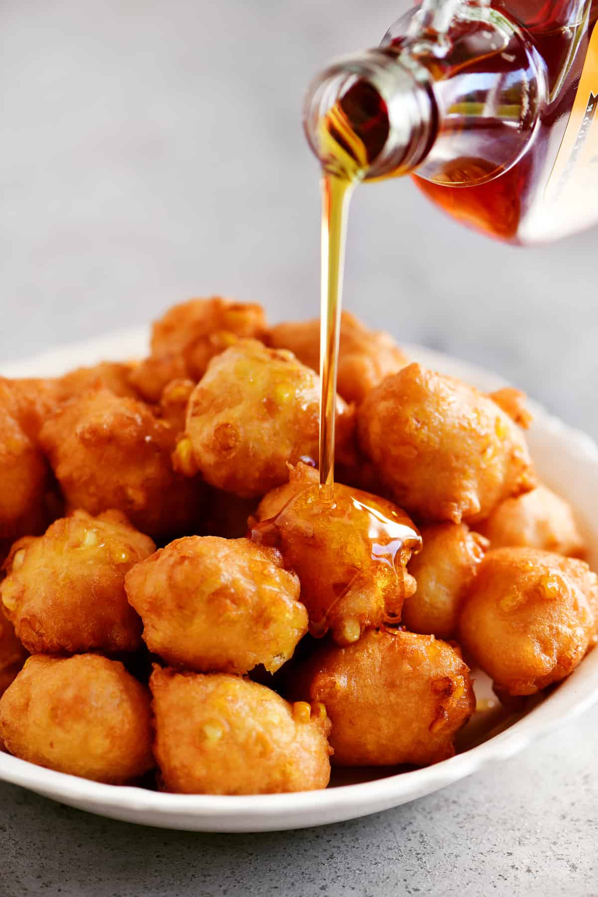 pouring maple syrup on corn fritters