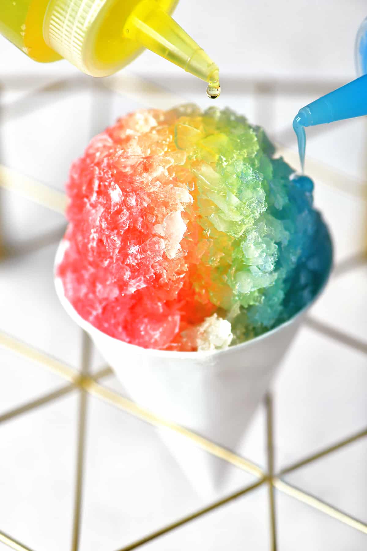 adding yellow and blue syrups to a classic snow cone