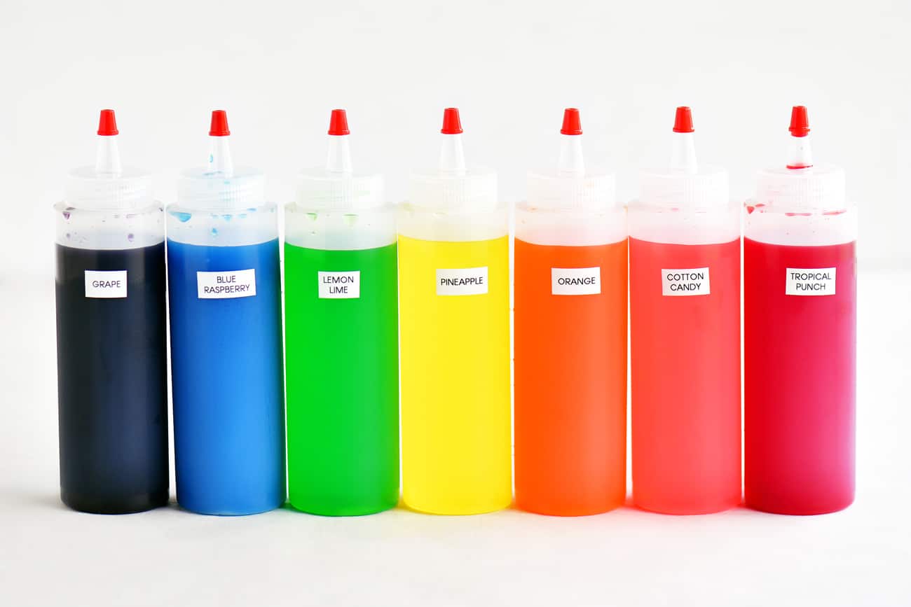 multiple squeeze bottles of snow cone syrup in the colors of the rainbow