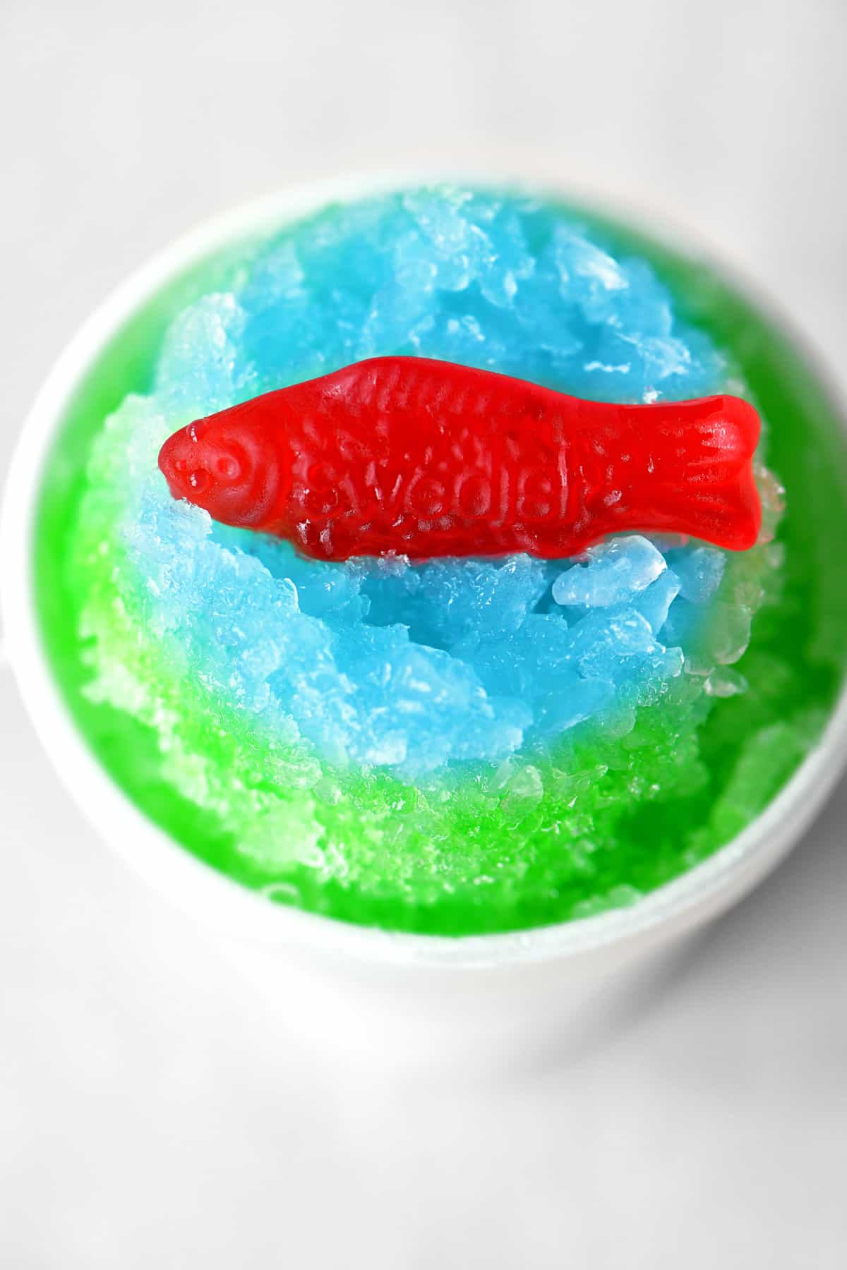 red gummy fish on blue and green ice in a cup