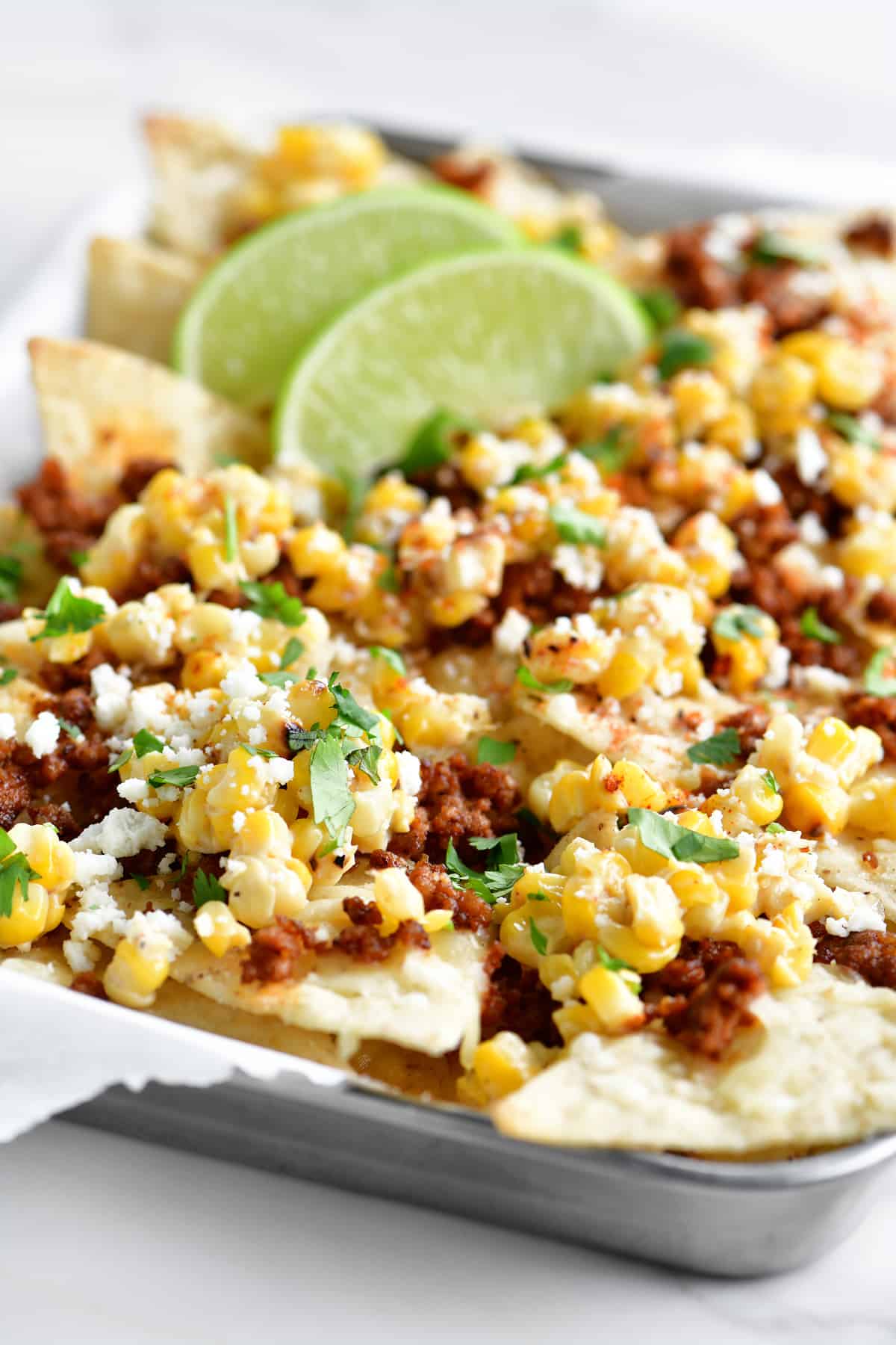 mexican street corn nachos in a tray with lime garnish