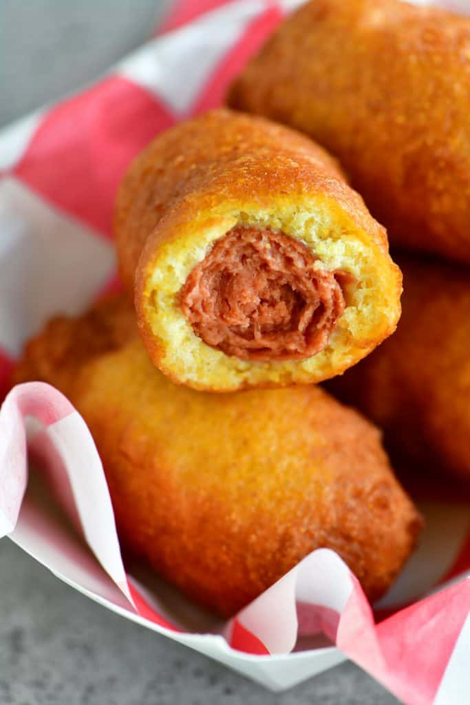 a close-up photo of a mini corn dog with a bite out of it