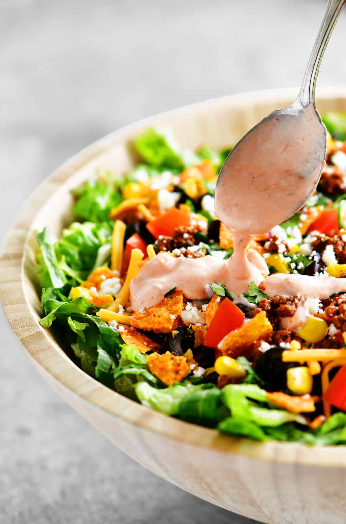 adding dressing to the salad with a spoon